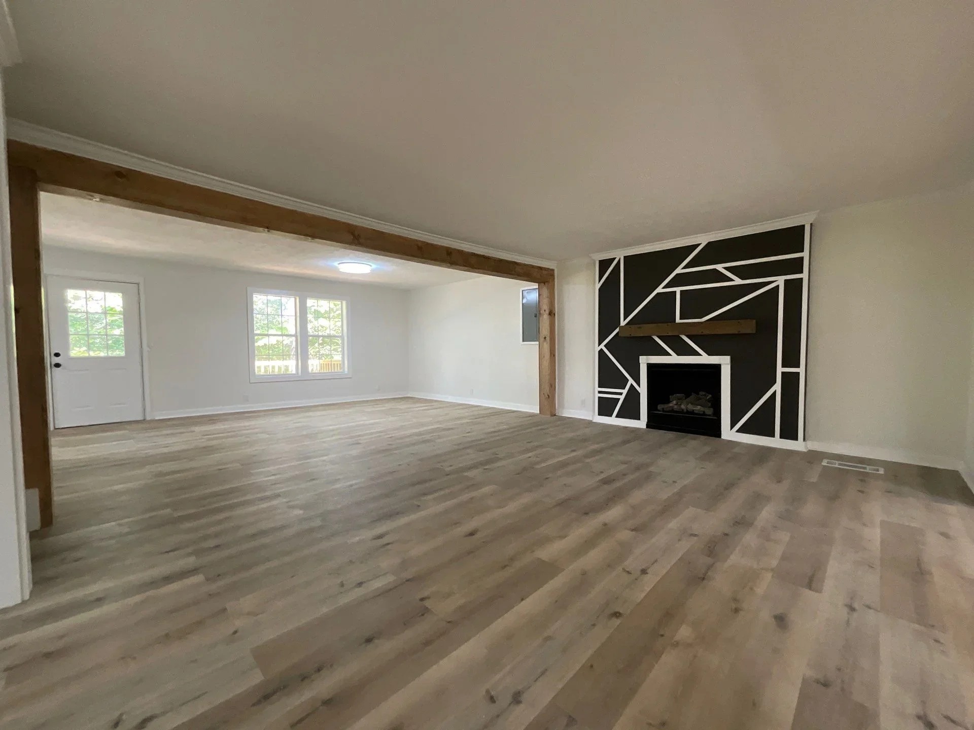Open living room with laminate flooring, geometric fireplace accent wall, and recessed lighting