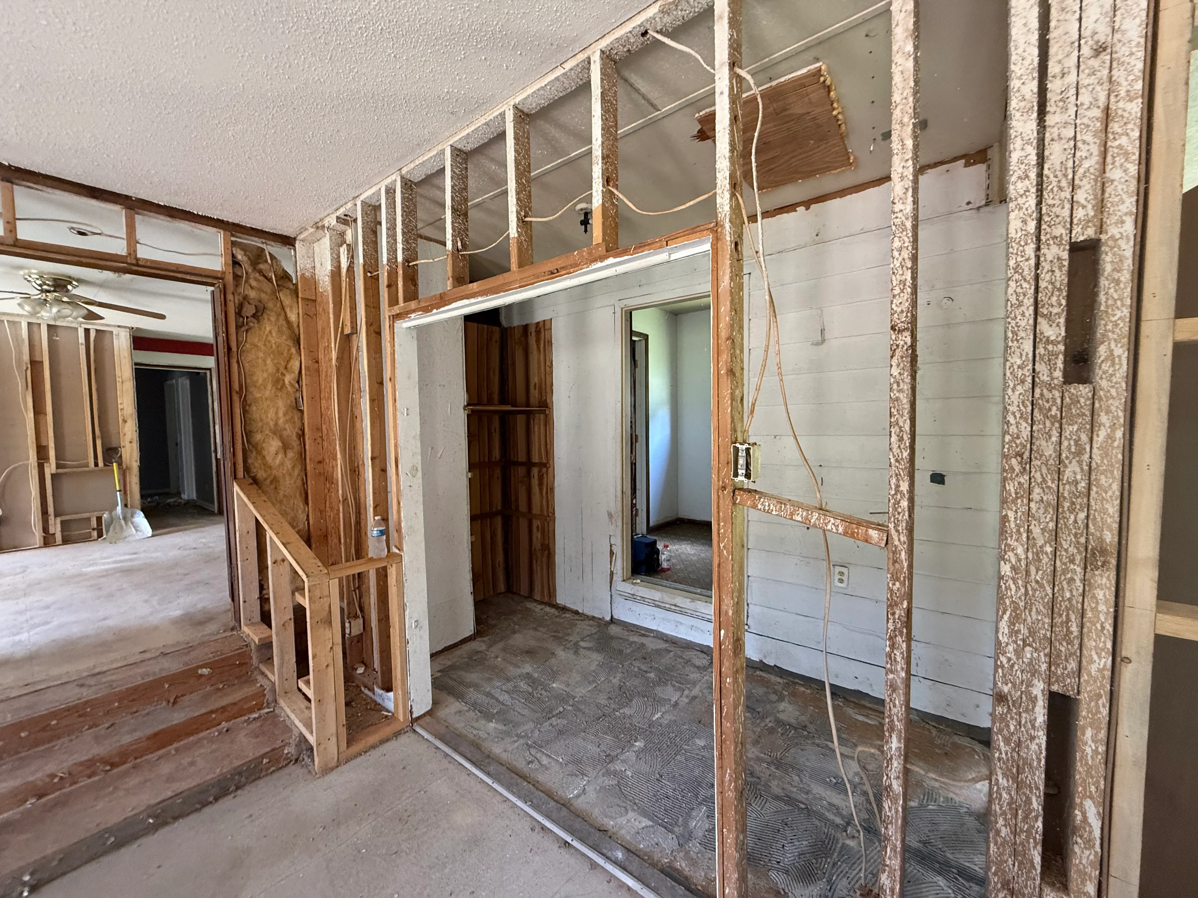 Interior framing with wooden studs, drywall installation, and electrical wiring in residential space