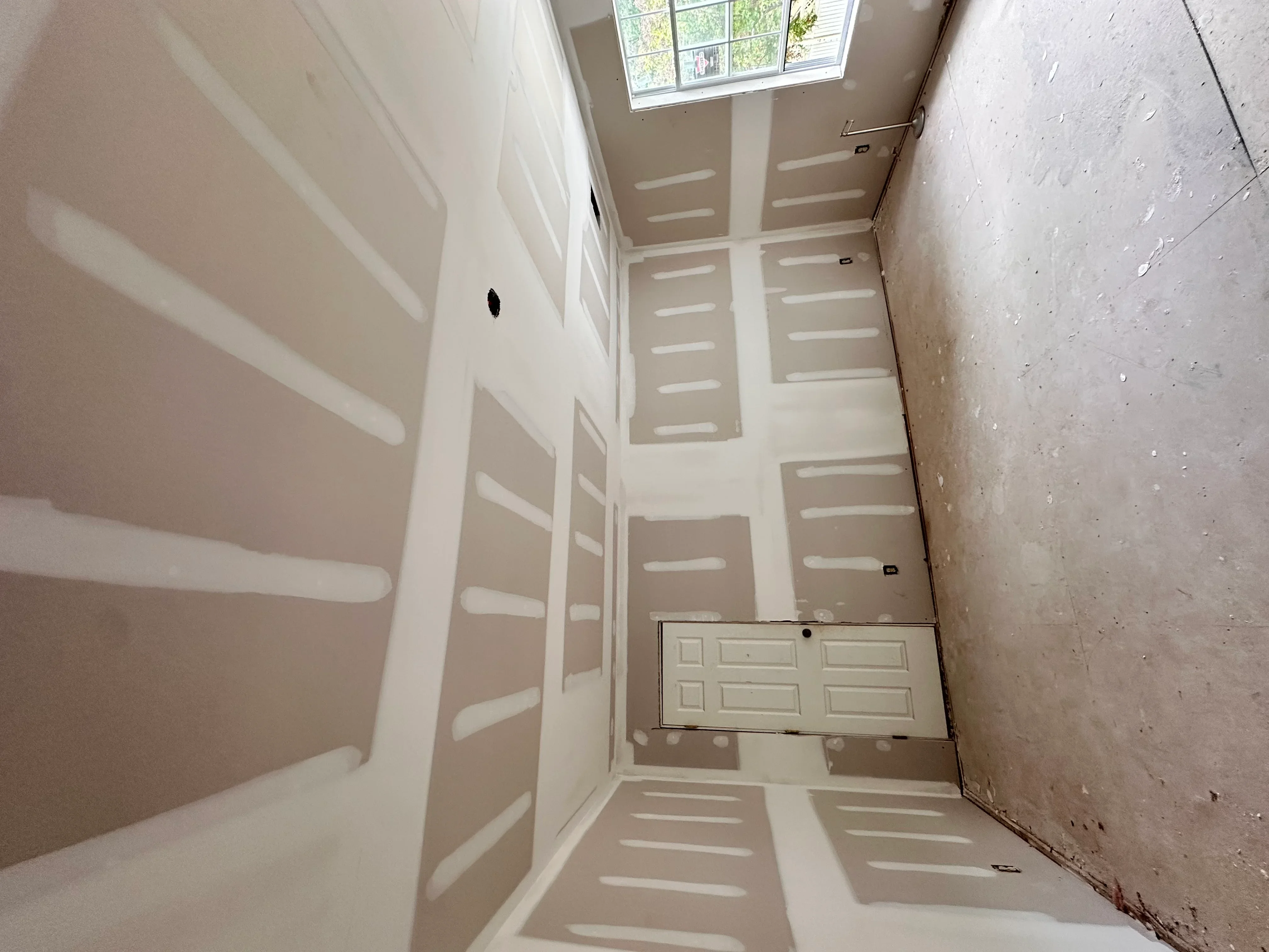 Drywall installation with taped seams and recessed light fixtures in residential interior