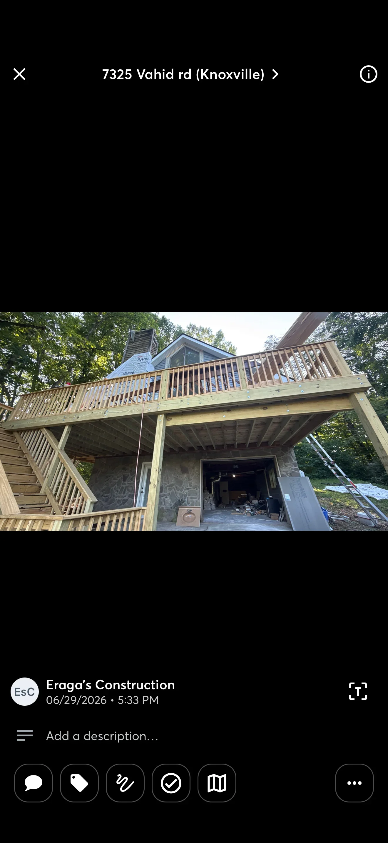 Two-story wood deck with covered patio, stone columns, and horizontal railings
