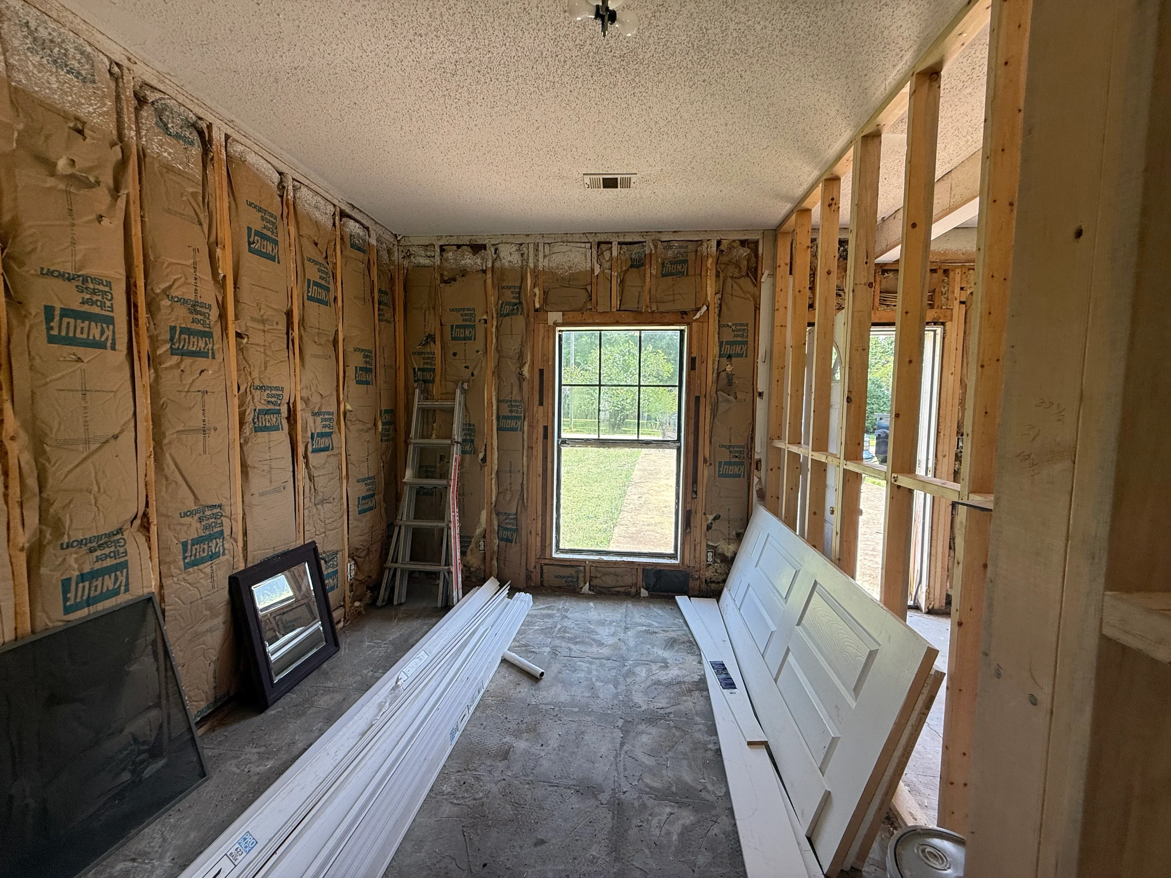 Interior framing with wood studs, insulation batts, and new door and window openings